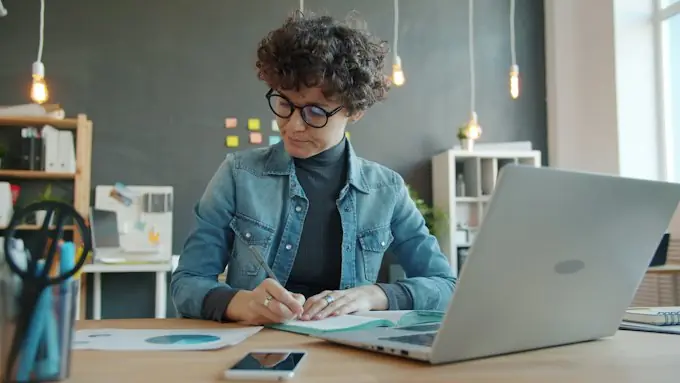 Secretaria de escuela trabajando en el escritorio con el cuaderno abierto