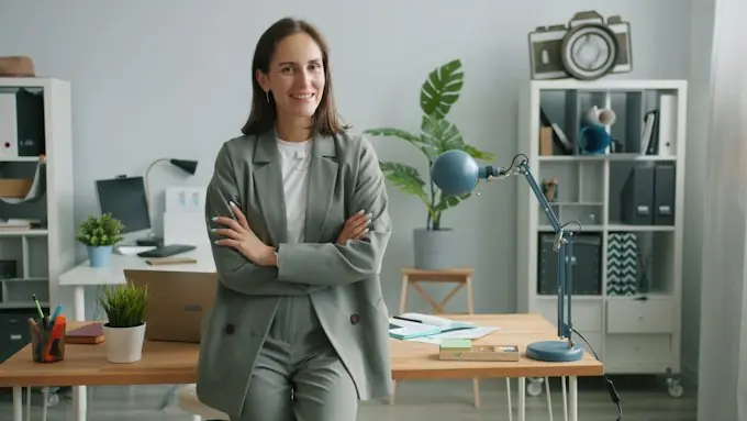 Gerenta en la oficina, sonriendo de brazos cruzados